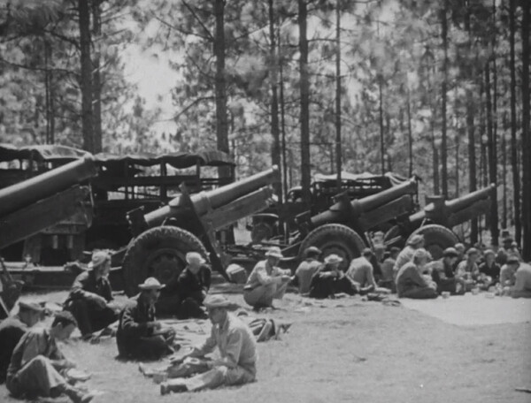 Soldiers eating around artillery 